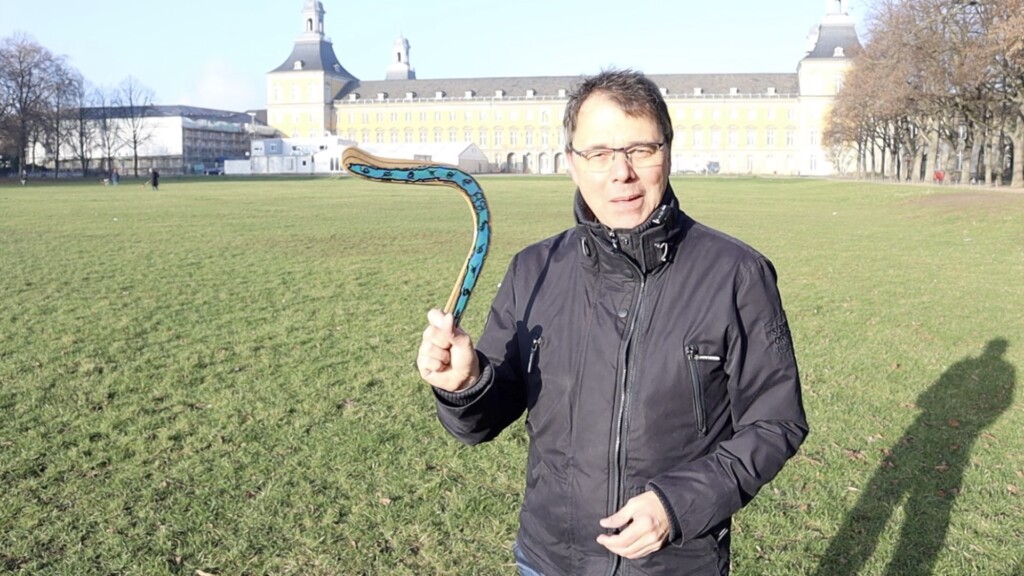 Robert Jautschus steht mit einem Bumerang auf einer Wiese und zeigt bewegte Coachingmethoden aus dem Inner Game für junge Führungskräfte.