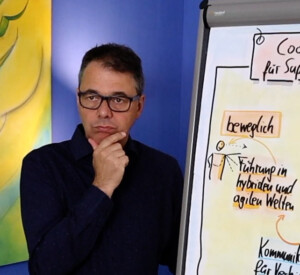 Robert Jautschus steht nachdenklich vor einer Flipchart und arbeitet an einem Modell dazu, wie Gefühle im Führungsalltag entstehen.